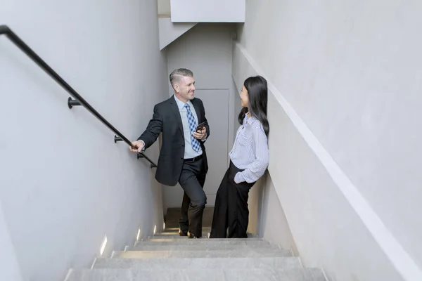 Деловые люди стоят и разговаривают на лестнице — стоковое фото