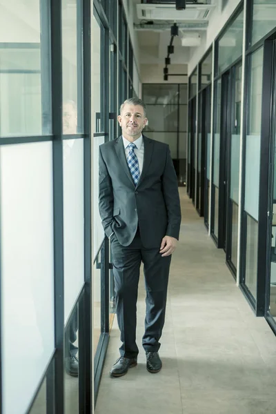 Caucásico hombre de negocios sonriendo apoyado en el vidrio — Foto de Stock