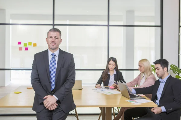 Confident caucasian manager in office seating on table — Stock Photo, Image