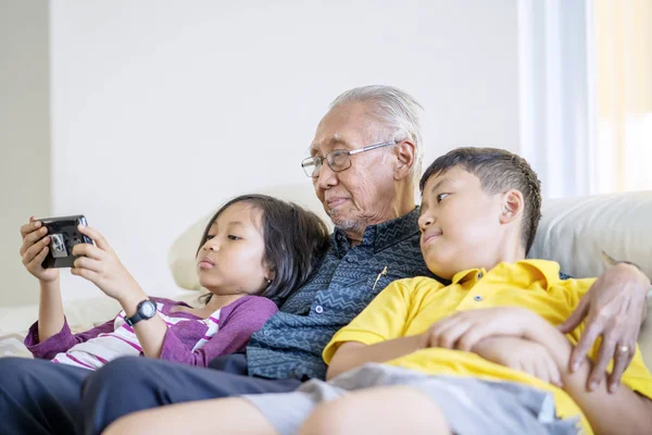 Grootvader en kleinkinderen kijken naar een film — Stockfoto