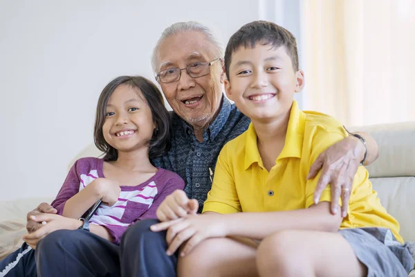 Счастливый дедушка обнимает своих внуков — стоковое фото