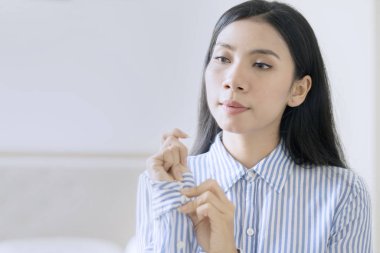 Çekici Asyalı iş kadını uzun kollu gömlek ilikliyor.