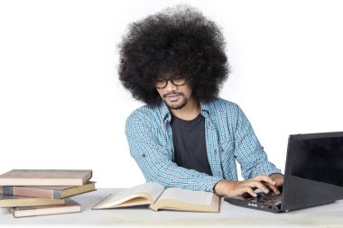 Büyük afro saçlı erkek öğrenci laptopta çalışıyor.