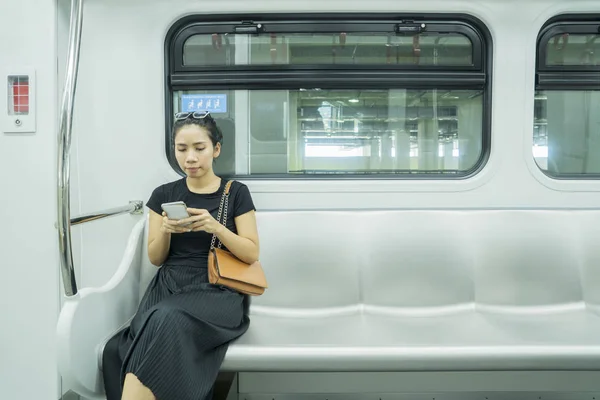 Ασιάτισσα γυναίκα που χρησιμοποιεί κινητό τηλέφωνο στο τρένο — Φωτογραφία Αρχείου