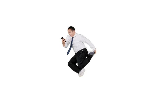 Businessman smiling looking at mobile phone while jumping isolated over white — Stock Photo, Image