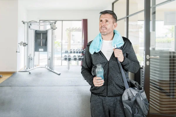 Middle aged attractive caucasian man with water bottle and sports bag at gym — ストック写真