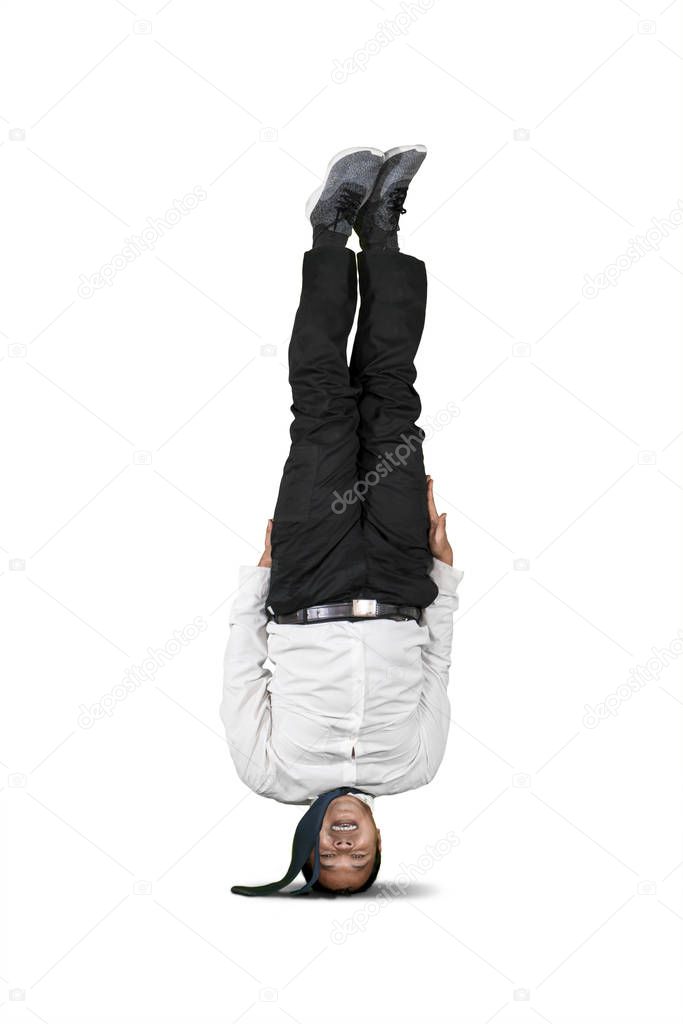 Businessman upside down doing headstand isolated over white