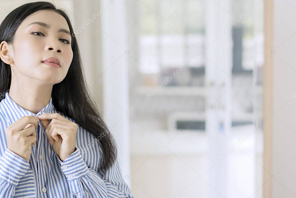 Cropped shot of young beautiful businesswoman buttoning up a shirt