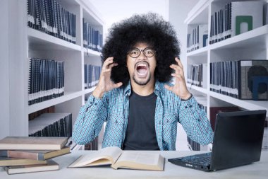 Büyük afro saçlı bir öğrenci kütüphanede bağırıyor.