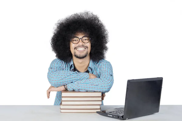 Studente met groot afro haar glimlachend met handen gekruist op de top van boeken in de bibliotheek — Stockfoto