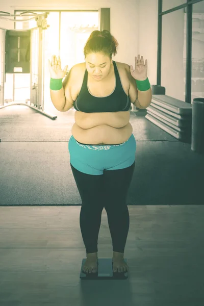 Fat Asian woman measuring her weight in a gym — Stock Photo, Image