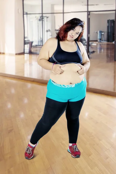 Grasso asiatico donna pizzicando il suo ventre in il gym — Foto Stock