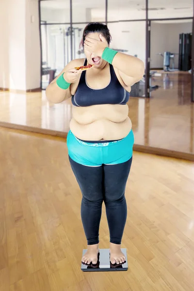 Fat woman facing health irony in the gym — Stock Photo, Image