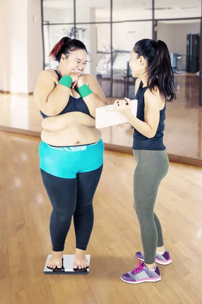 Mujer gorda mira su peso corporal felizmente en el gimnasio —  Fotos de Stock