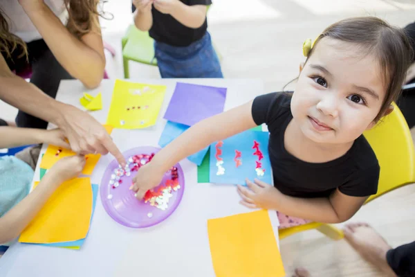 Aluno sorrindo para a câmera enquanto cria origamis — Fotografia de Stock