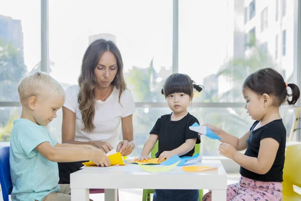 Professora ensinando seus alunos a dobrar origamis — Fotografia de Stock