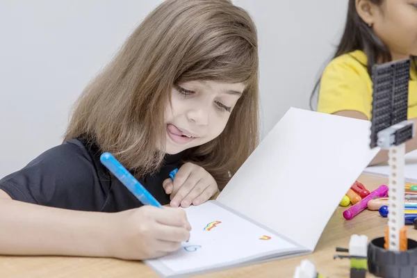 Két gyerek érdekesen rajzol a könyvére. — Stock Fotó