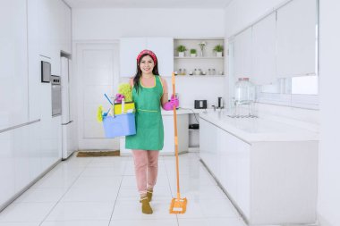 Güzel Asyalı kadın temizlik malzemeleri taşıyor.