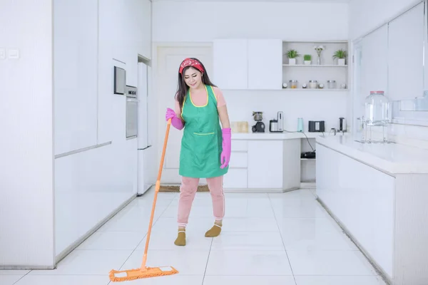 Mulher asiática bonita esfregando os pisos da cozinha — Fotografia de Stock