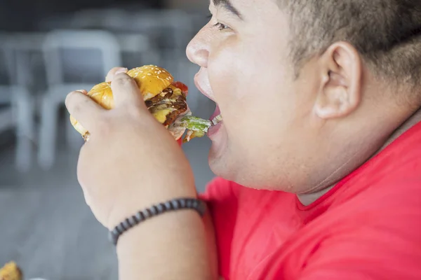 Detailní záběr tlusté asijské muž jíst burger šťastně — Stock fotografie