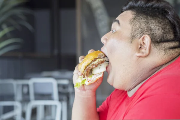 Zbliżenie z tłuszcz Azji człowiek gapienie a cheeseburger — Zdjęcie stockowe