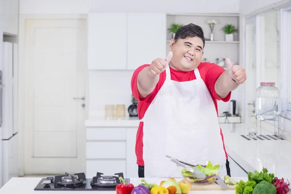 Fat Asian man doing thumbs up pose in the kitchen — Stock Photo, Image
