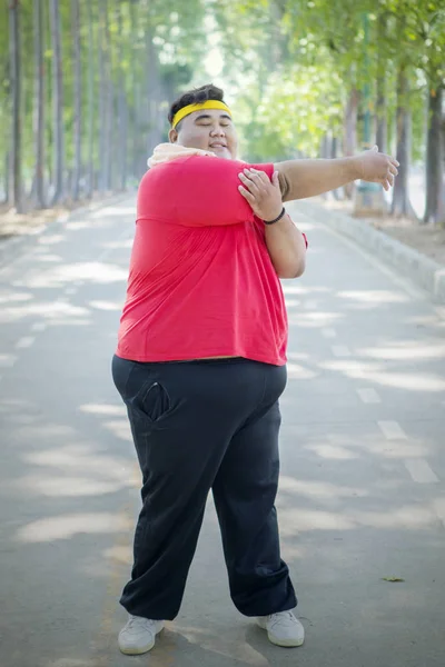 Fet asiatisk man trycker sin högra armbåge till vänster — Stockfoto