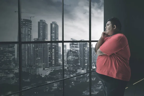 Fat Asian man staring at the cityscape pensively