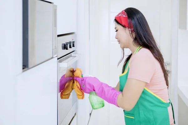 Sidovy av asiatisk kvinna rengöring en ugn — Stockfoto