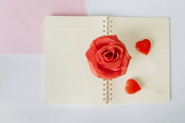 Дві любовні цукерки і троянда, поміщена на блокнот — стокове фото