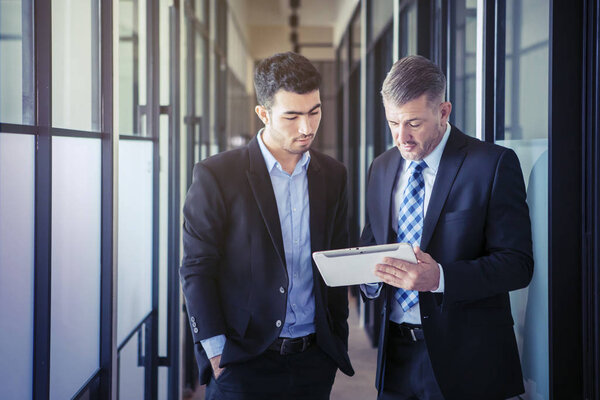 Босс показывает документы своему азиатскому сотруднику
