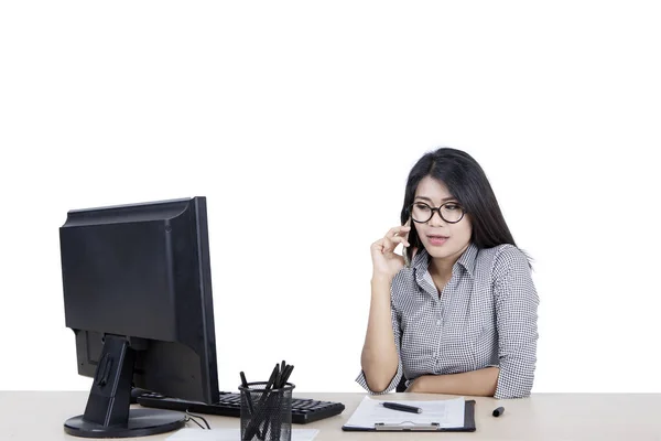 Mulher chamando alguém enquanto trabalhava em seu desktop — Fotografia de Stock