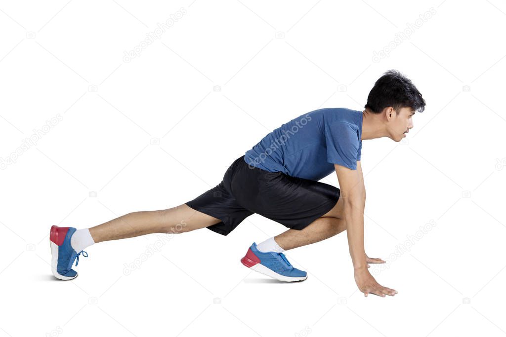 Side view of man crouching and preparing to run