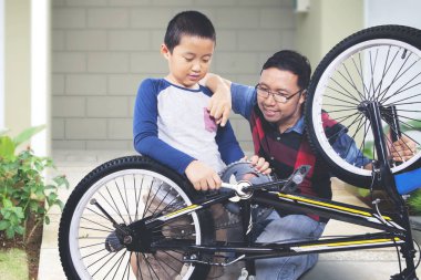 Çocuk, babasıyla ilginç bir şekilde bisikletini tamir ediyor.