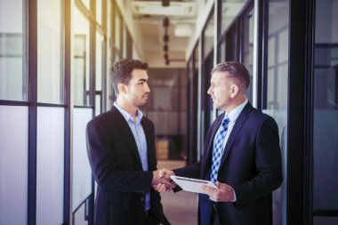 İşadamı portresi çalışanların elini sıkıyor.