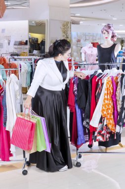 Kadın alışveriş merkezinde kıyafet seçimini yapıyor.