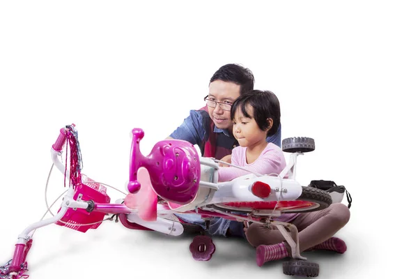Азіатський чоловік керує своєю донькою, як полагодити свій велосипед. — стокове фото