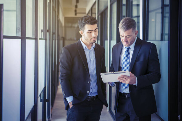 Бизнесмен показывает документы своему азиатскому сотруднику
