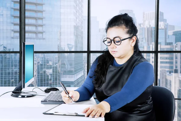 Empresária escrevendo tarefas de trabalho em seu escritório — Fotografia de Stock