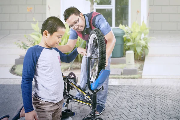 家の庭で息子と自転車を修理する男 — ストック写真