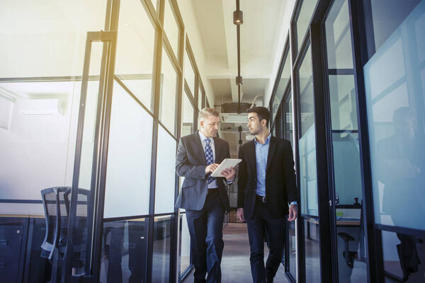 Человек разговаривает со своим партнером, держа планшет
