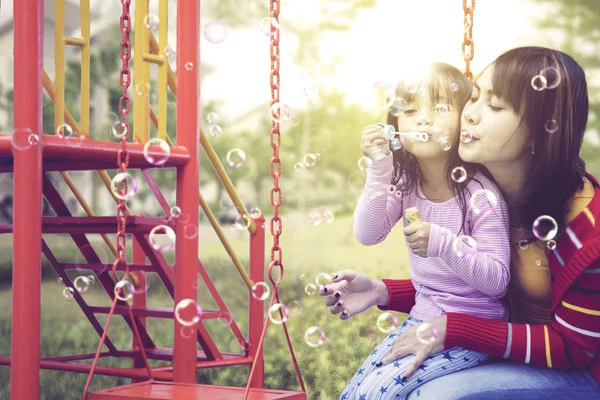 Moeder houdt haar dochter gelukkig tijdens het swingen — Stockfoto