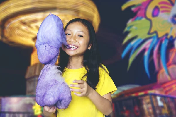 Schattig meisje bijten een suikerspin in een park — Stockfoto