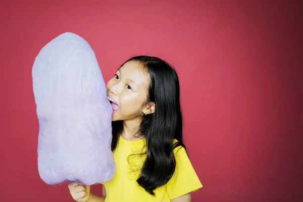 Adorabile ragazza mangiare e mordere uno zucchero filato — Foto Stock