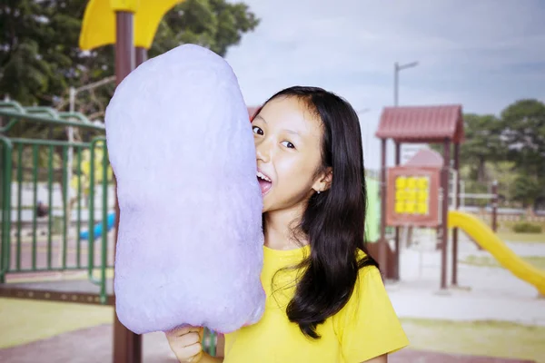 Asian girl biting a cotton candy at the playground — Stock Photo, Image