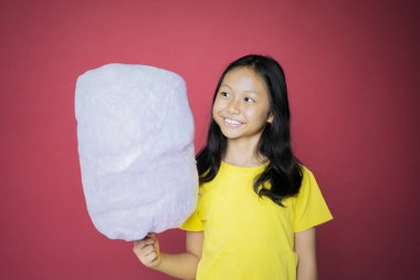 Kız elinde pamuk şeker tutarken neşeyle gülümsüyor