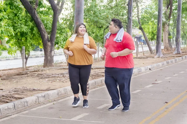 Fettes asiatisches Paar plaudert freudig beim Joggen — Stockfoto