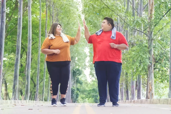 Tlustý asijské pár dělá high five zatímco jogging — Stock fotografie