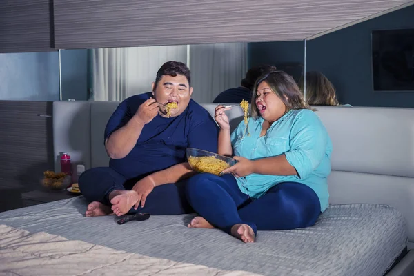 Televizyon izlerken erişte yiyen şişman Asyalı çift. — Stok fotoğraf