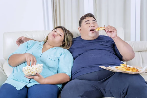 Pizza yiyip patlamış mısır yiyen şişman Asyalı çift. — Stok fotoğraf